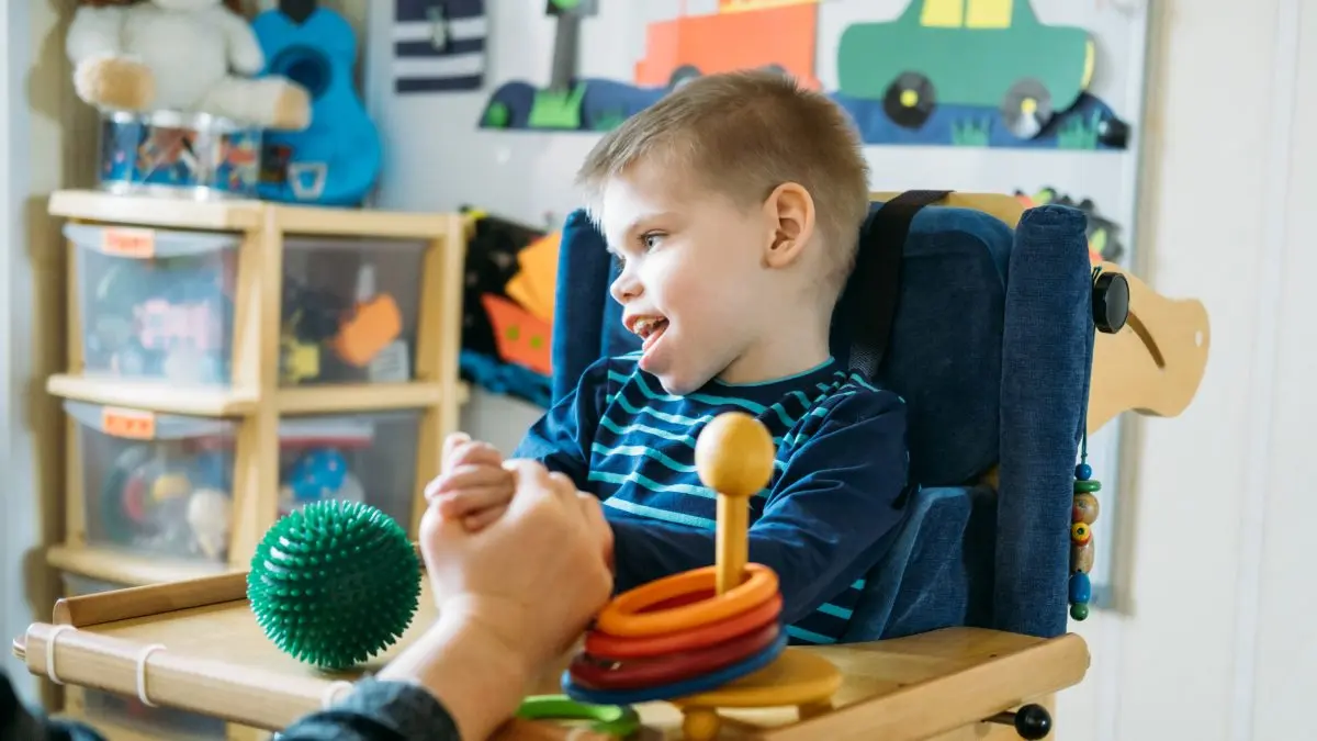 Jeune garçon atteint de paralysie cérébrale dans une chaise haute.
