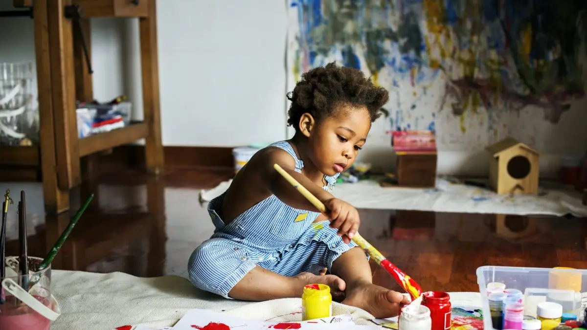 petit enfant noir jouant avec de la peinture 